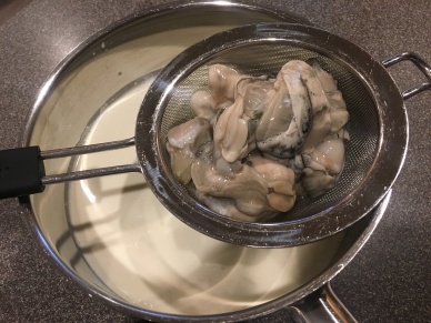 Draining oysters into heavy cream.