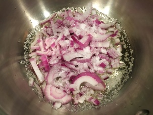 Red onion and Kosher salt added to saucier with olive oil.