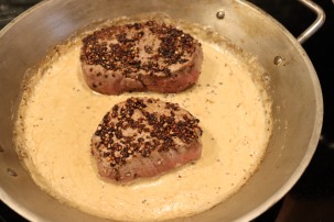 Steaks added back to the pan with the sauce.