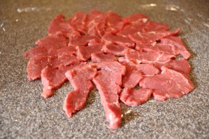 Sliced meat forming a disc on plastic wrap.
